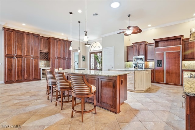 kitchen with a large island, built in appliances, pendant lighting, and backsplash