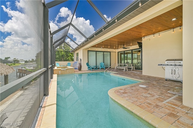 view of pool with a patio, area for grilling, ceiling fan, and glass enclosure