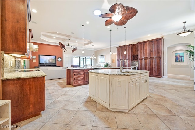 kitchen with decorative backsplash, a kitchen island with sink, ornamental molding, sink, and decorative light fixtures