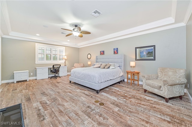 bedroom with crown molding, a tray ceiling, light wood-type flooring, and ceiling fan