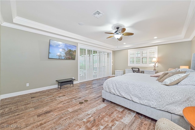 bedroom featuring crown molding, a tray ceiling, wood-type flooring, and ceiling fan