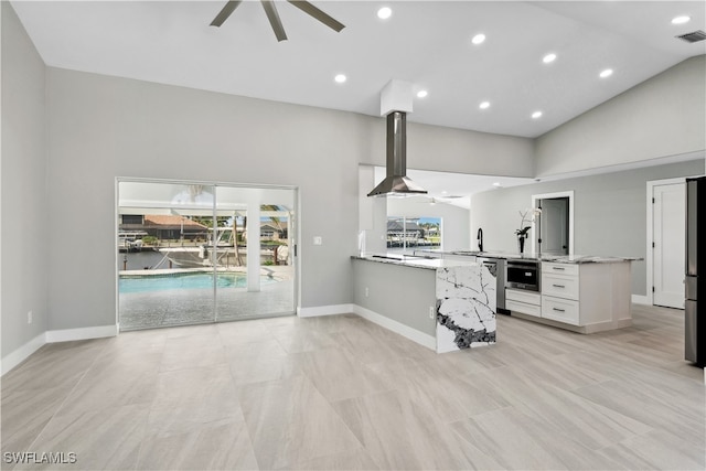 kitchen with white cabinets, kitchen peninsula, high vaulted ceiling, and wall chimney range hood