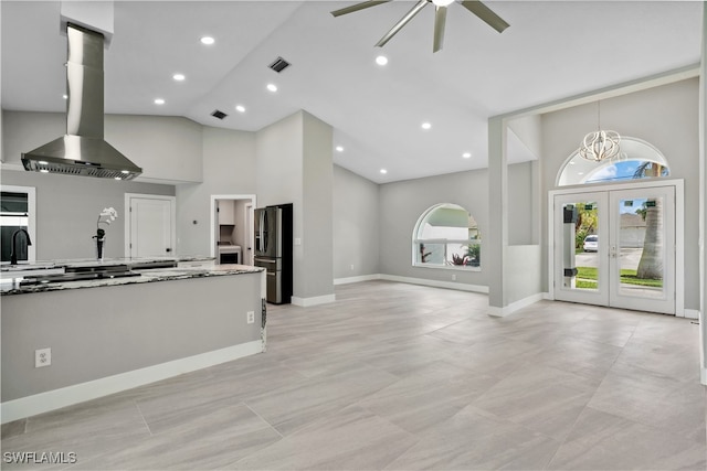 kitchen featuring high vaulted ceiling, french doors, ceiling fan with notable chandelier, stainless steel refrigerator with ice dispenser, and island exhaust hood