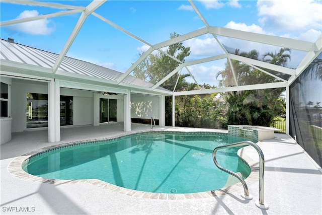 view of pool featuring ceiling fan, a patio area, glass enclosure, and a hot tub