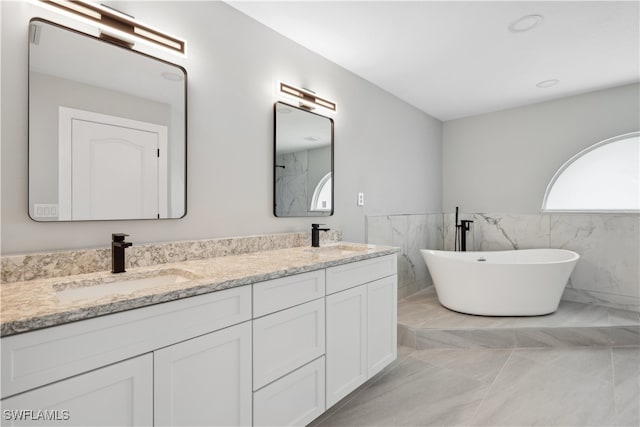 bathroom featuring vanity, a bathtub, tile patterned floors, and tile walls