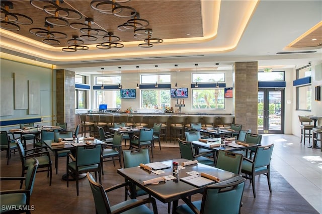 tiled dining area with french doors, a raised ceiling, and wooden ceiling