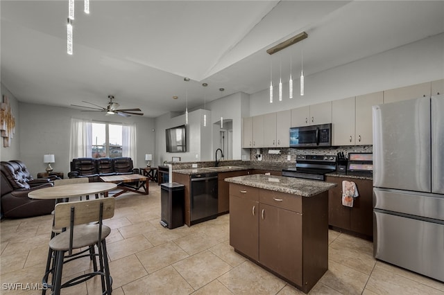 kitchen featuring sink, appliances with stainless steel finishes, decorative light fixtures, and a center island