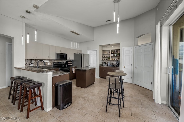 kitchen with hanging light fixtures, kitchen peninsula, stainless steel appliances, and tasteful backsplash