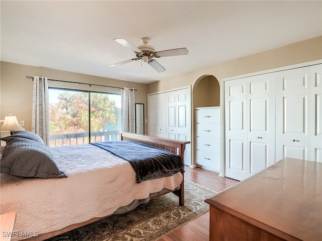 bedroom featuring access to outside, hardwood / wood-style floors, two closets, and ceiling fan