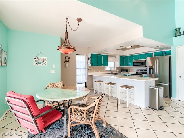 kitchen with light tile patterned flooring, sink, kitchen peninsula, appliances with stainless steel finishes, and green cabinetry