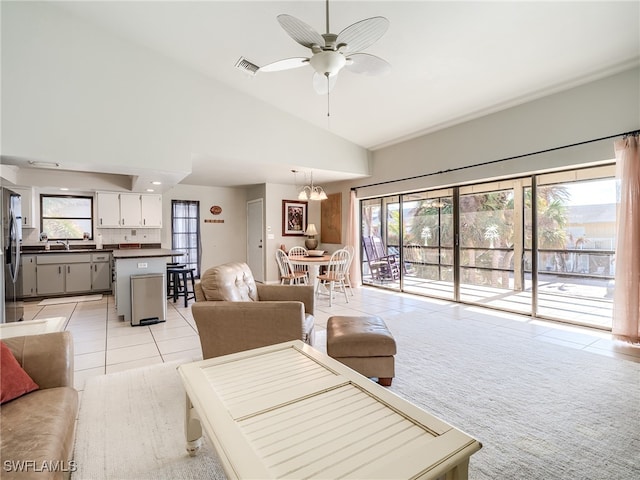 living room with high vaulted ceiling, sink, light tile patterned floors, and ceiling fan with notable chandelier