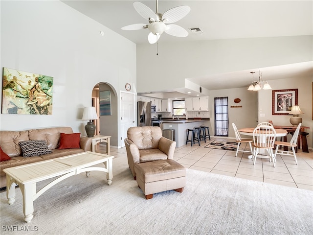 living room featuring ceiling fan with notable chandelier, light tile patterned floors, and high vaulted ceiling