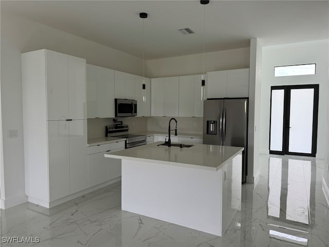 kitchen with hanging light fixtures, white cabinetry, a kitchen island with sink, sink, and stainless steel appliances