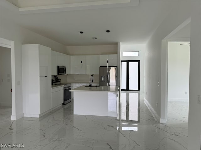 kitchen with a kitchen island with sink, sink, white cabinets, pendant lighting, and appliances with stainless steel finishes