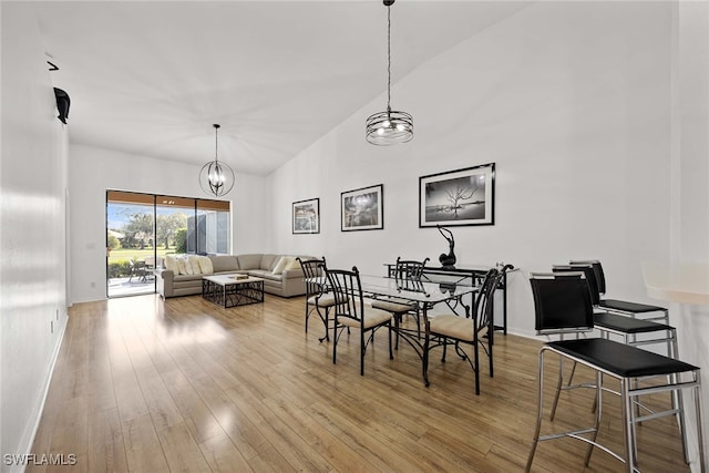 dining room featuring a notable chandelier, light wood-type flooring, and vaulted ceiling