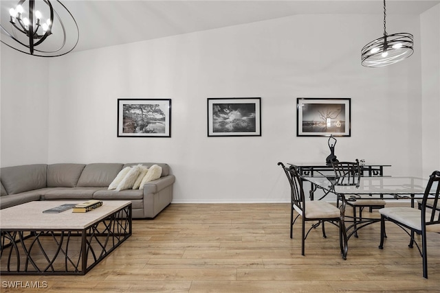 dining room featuring a chandelier, vaulted ceiling, and light hardwood / wood-style flooring