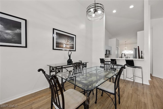 dining area with a chandelier, wood-type flooring, and sink