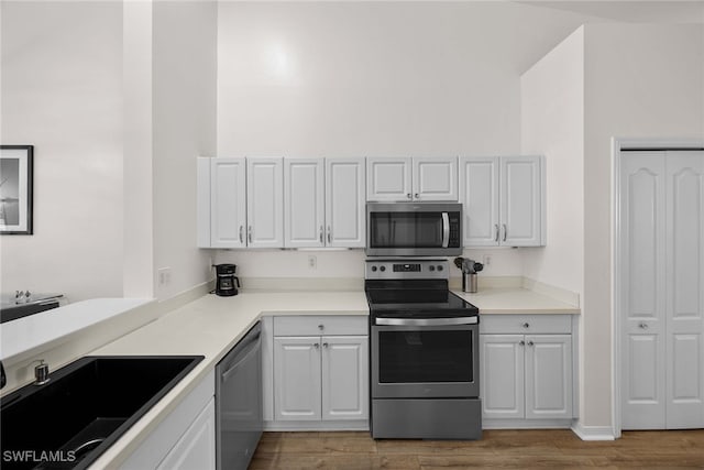 kitchen with white cabinetry, sink, light hardwood / wood-style floors, and appliances with stainless steel finishes