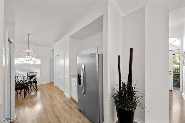 kitchen with pendant lighting, a chandelier, stainless steel fridge with ice dispenser, light hardwood / wood-style floors, and white cabinetry