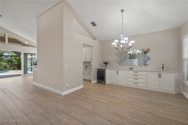 interior space featuring light hardwood / wood-style flooring, a notable chandelier, high vaulted ceiling, and beverage cooler