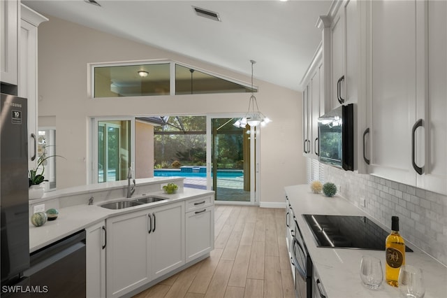 kitchen with white cabinets, vaulted ceiling, light hardwood / wood-style floors, black electric stovetop, and sink