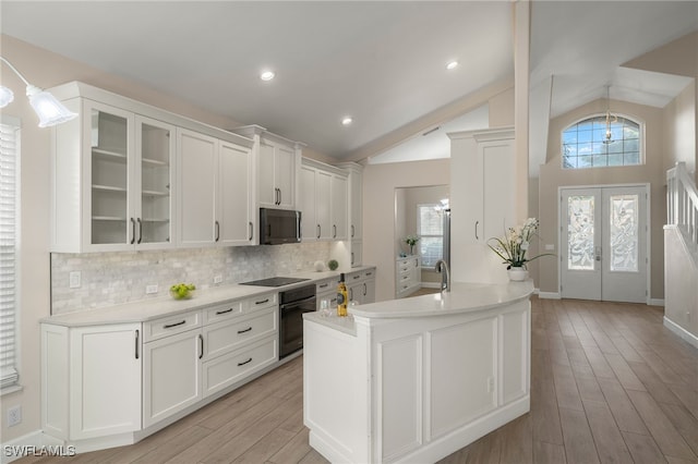 kitchen with lofted ceiling, french doors, black appliances, light wood-type flooring, and white cabinetry