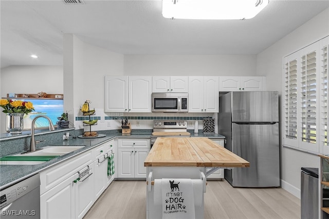 kitchen with decorative backsplash, light hardwood / wood-style flooring, sink, white cabinetry, and appliances with stainless steel finishes