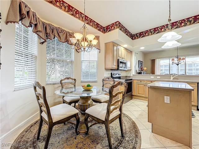 tiled dining space featuring a healthy amount of sunlight, sink, and an inviting chandelier