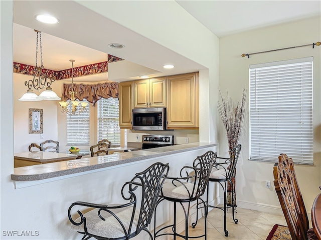 kitchen with stainless steel appliances, hanging light fixtures, a breakfast bar, and kitchen peninsula