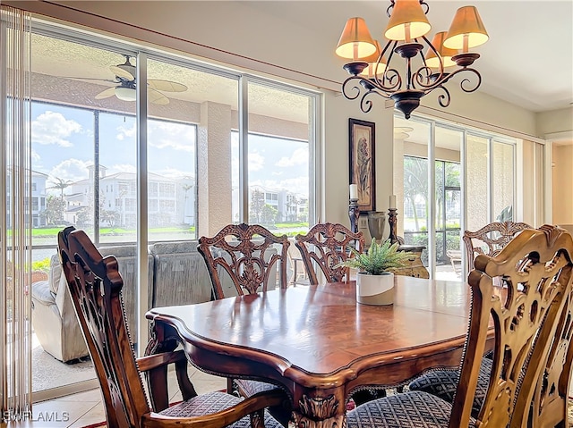 tiled dining room featuring ceiling fan with notable chandelier and a healthy amount of sunlight