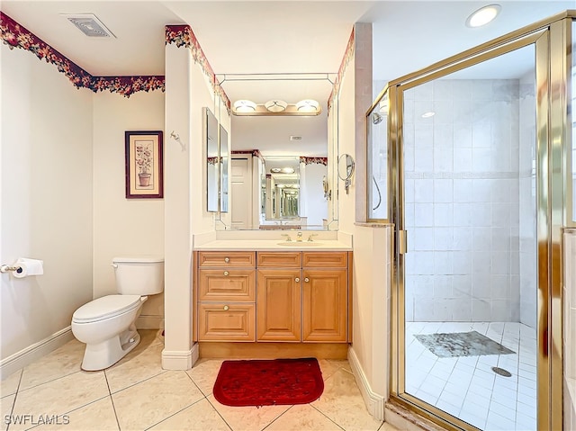 bathroom featuring toilet, vanity, tile patterned floors, and a shower with door