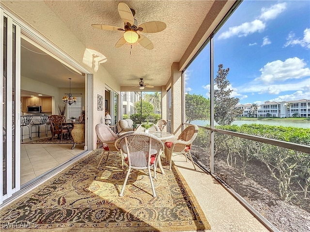 sunroom / solarium featuring ceiling fan with notable chandelier and a water view