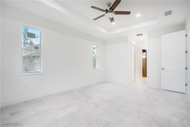 spare room featuring a healthy amount of sunlight, a tray ceiling, and ceiling fan