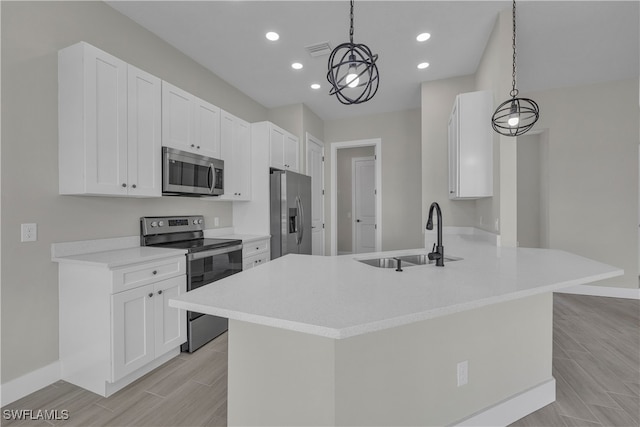 kitchen featuring kitchen peninsula, appliances with stainless steel finishes, white cabinetry, pendant lighting, and sink