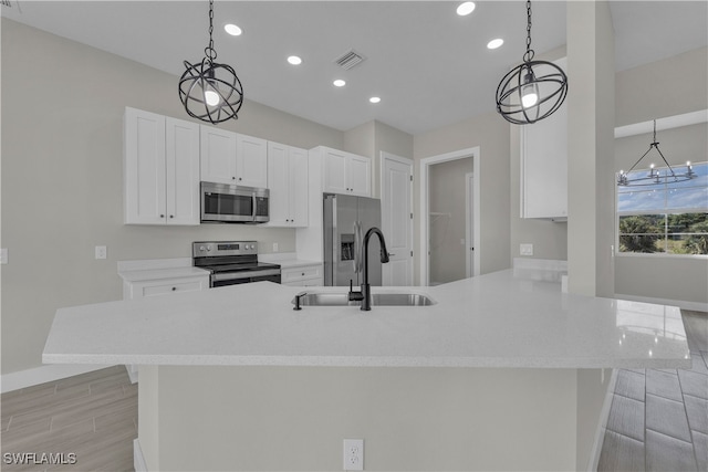 kitchen featuring white cabinets, appliances with stainless steel finishes, a chandelier, sink, and decorative light fixtures