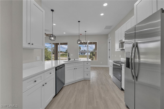 kitchen with kitchen peninsula, stainless steel appliances, decorative light fixtures, white cabinets, and light hardwood / wood-style flooring