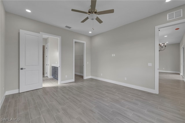 unfurnished bedroom with a walk in closet, light wood-type flooring, ensuite bathroom, ceiling fan with notable chandelier, and a closet