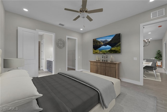 bedroom with ceiling fan with notable chandelier, light hardwood / wood-style floors, and ensuite bath