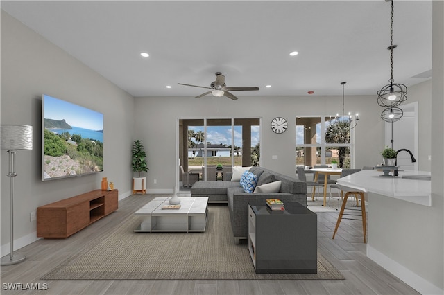 living room featuring sink, ceiling fan with notable chandelier, and hardwood / wood-style floors