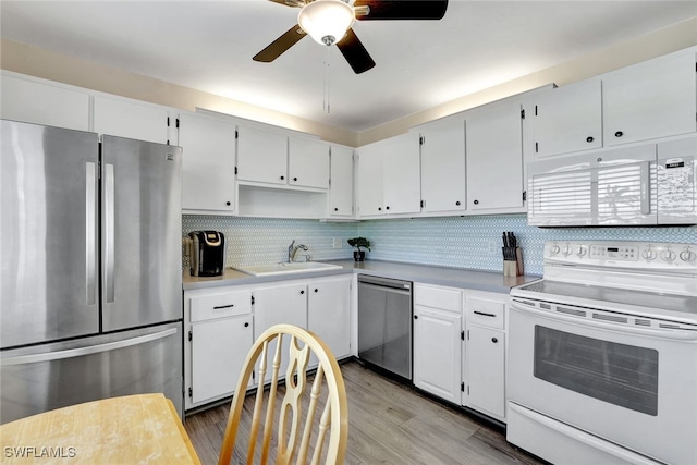 kitchen with wood finished floors, a sink, stainless steel appliances, light countertops, and backsplash