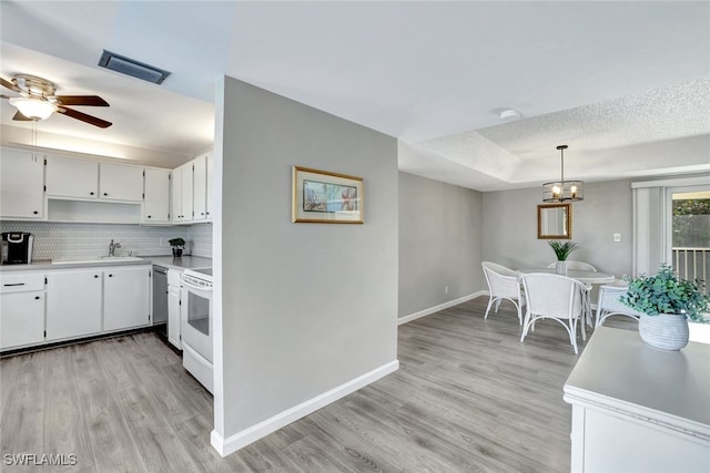 kitchen with decorative light fixtures, white cabinetry, light hardwood / wood-style floors, electric range, and a tray ceiling