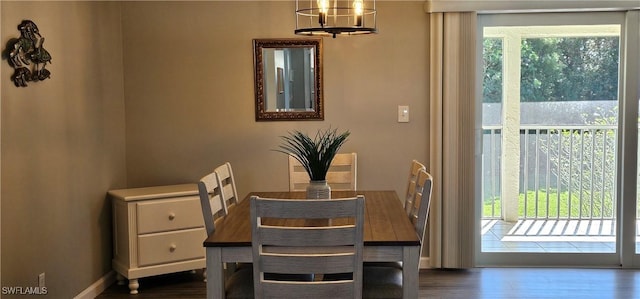 dining space featuring baseboards, a chandelier, and dark wood-style flooring