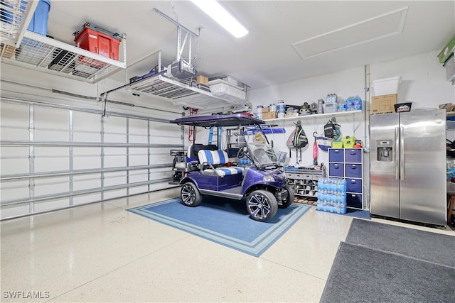 garage with a garage door opener and stainless steel fridge