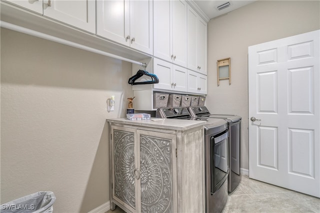 laundry room with cabinets, washing machine and clothes dryer, and light tile patterned flooring