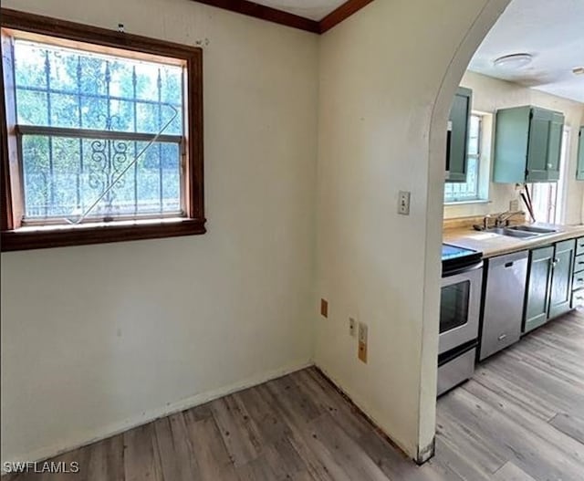 kitchen with sink, crown molding, appliances with stainless steel finishes, and light hardwood / wood-style flooring