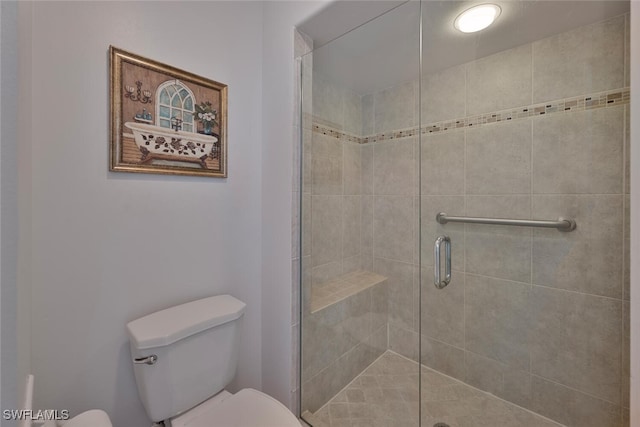 bathroom featuring toilet and a shower with shower door