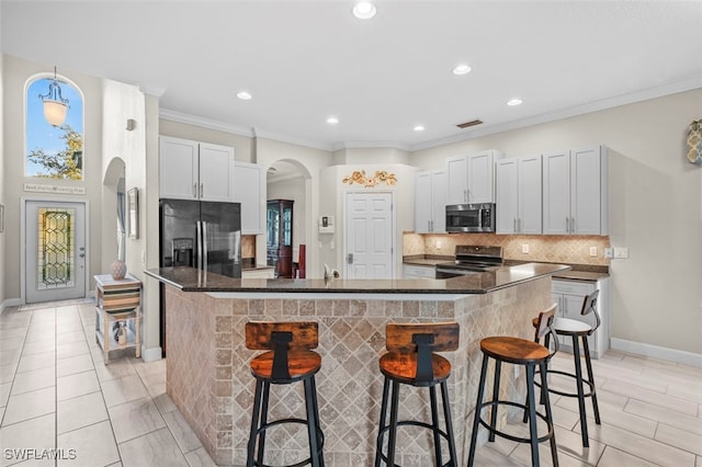 kitchen with a center island, white cabinetry, stainless steel appliances, and a breakfast bar area