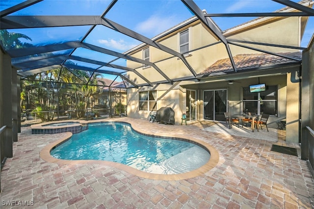 view of pool with an in ground hot tub, glass enclosure, and a patio area