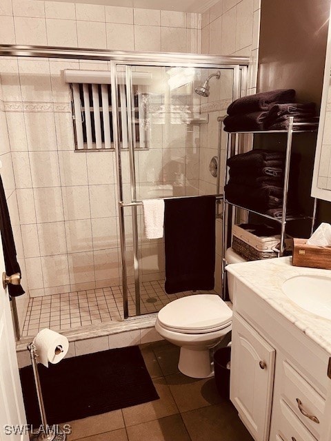 bathroom with vanity, toilet, tile patterned floors, and a shower with door