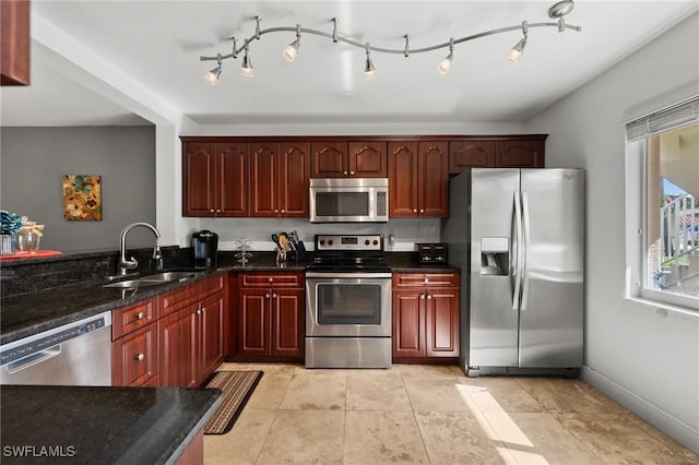 kitchen featuring light tile patterned floors, sink, appliances with stainless steel finishes, and dark stone counters